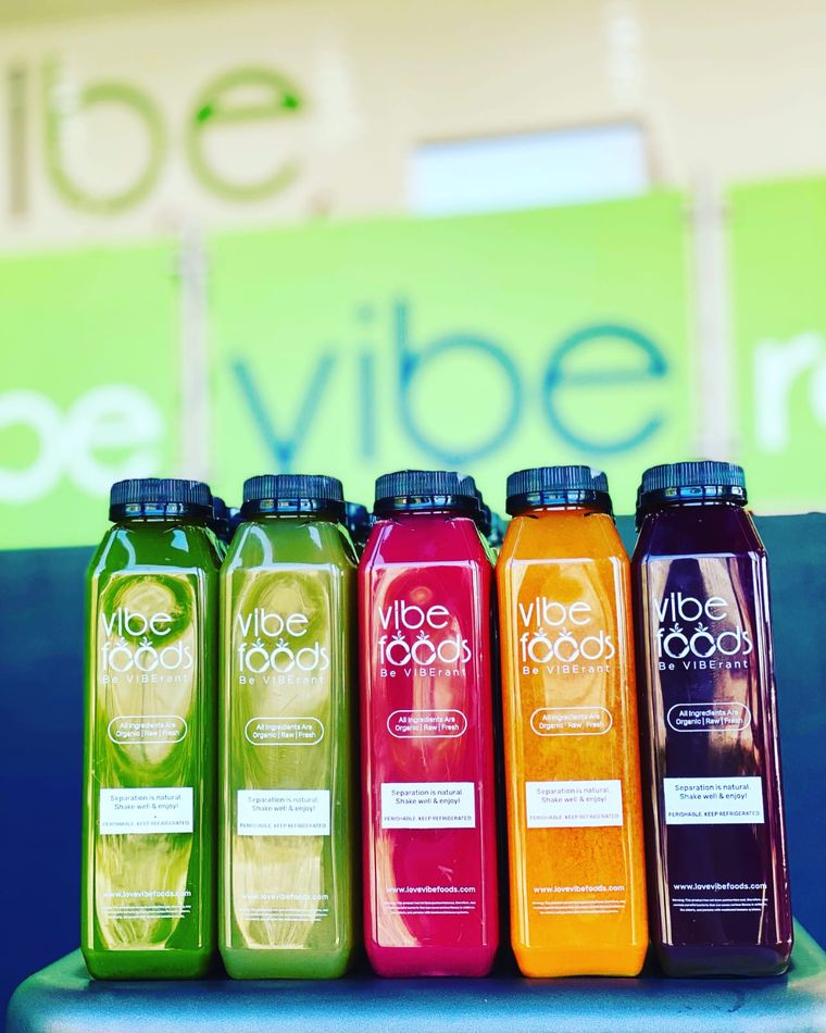 Five bottles of Vibe Foods organic juice in green, red, orange and purple